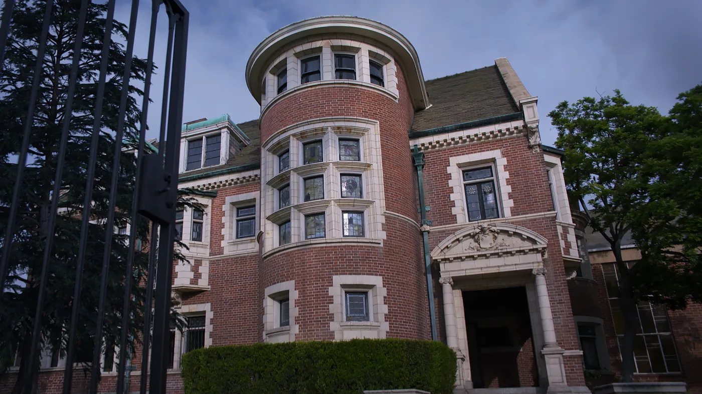 The familiar Victorian house seen in American Horror Stories stands behind its black front gate in an official Disney and FX publicity still.