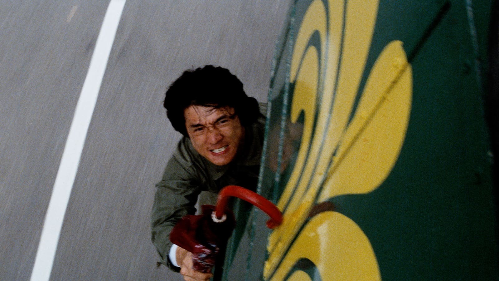 Jackie Chan clinging to the side of a moving bus in Police Story.