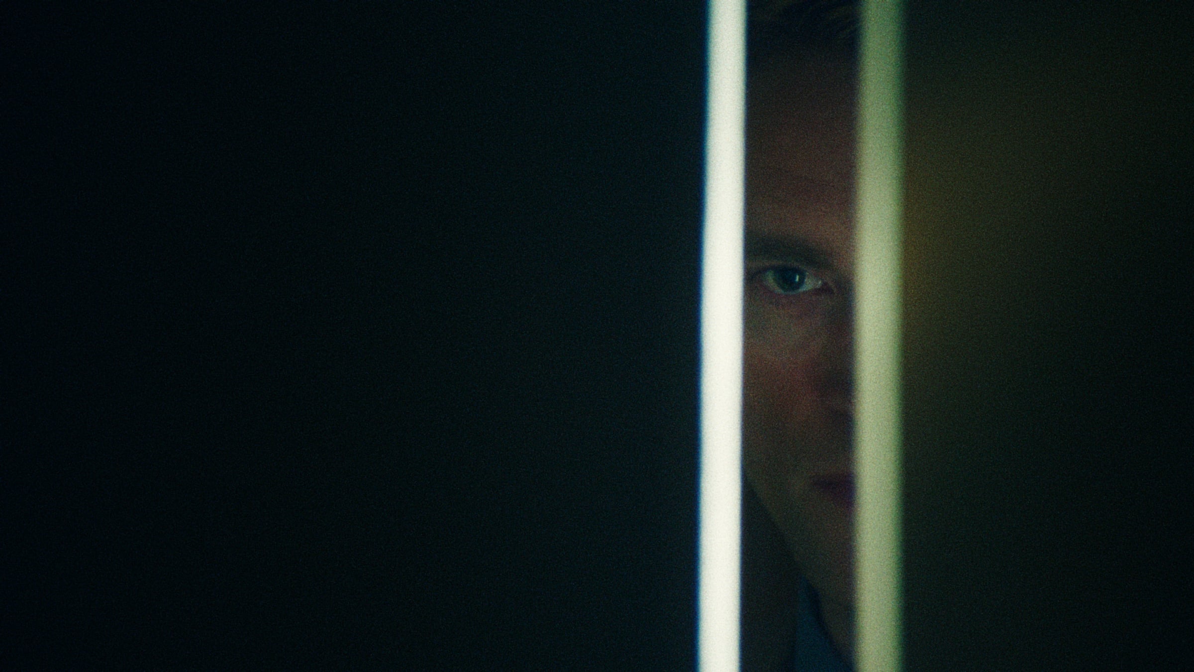 Robert Pattinson as Chris Hansen in A24's Primetime, seen through a narrow doorway