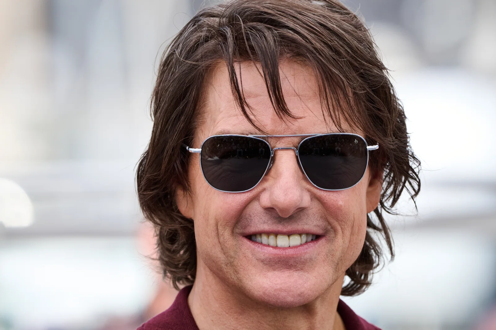 Tom Cruise smiling and wearing sunglasses at the 2025 Cannes Film Festival.