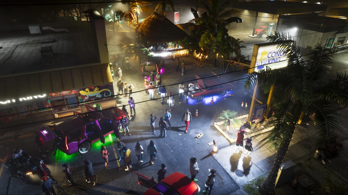 Official GTA VI promotional image showing people and illuminated vehicles gathered outside a tropical roadside business at night.