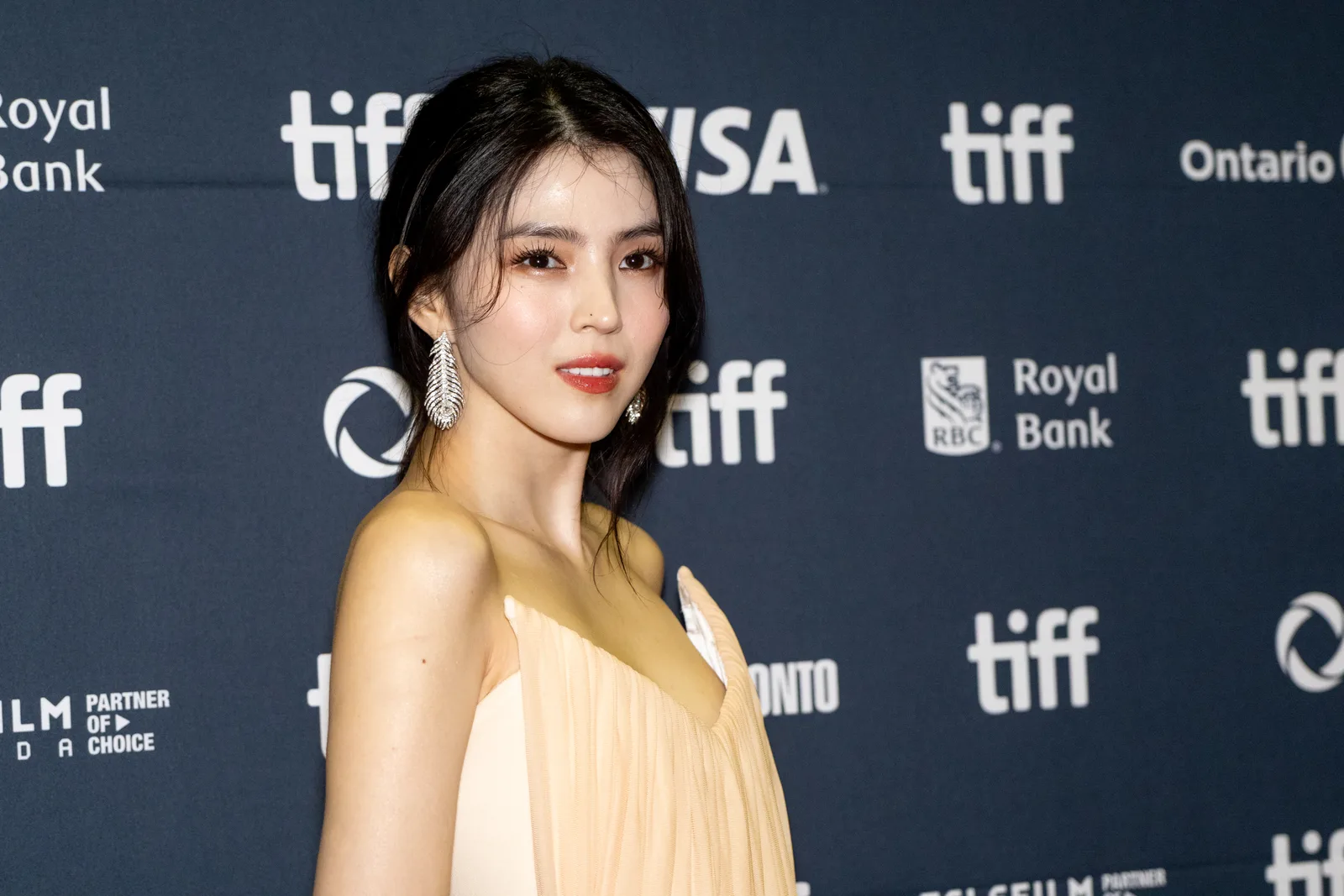 Han So-hee wearing a pale dress in front of a TIFF backdrop.