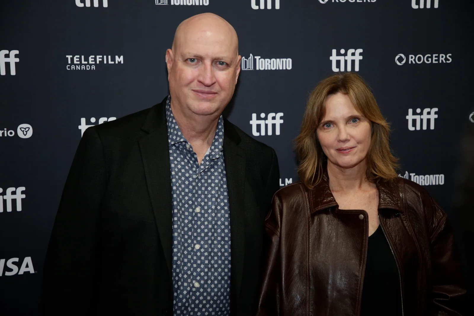 The Night Agent creator Shawn Ryan, left, and Eileen Myers stand in front of a Toronto International Film Festival backdrop in September 2026.